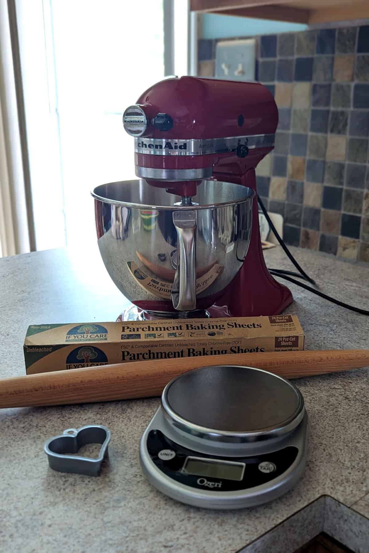 stand mixer, rolling pin, parchment paper, digital scale, and heart-shaped cookie cutter