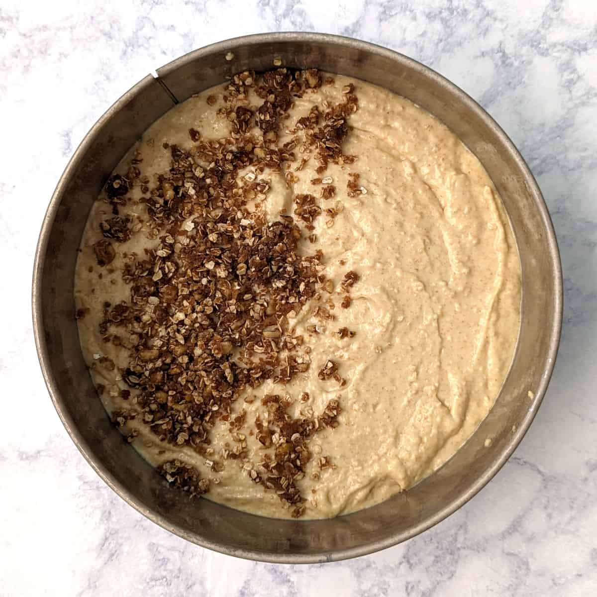 sour cream coffee cake batter in the pan, partially topped with streusel