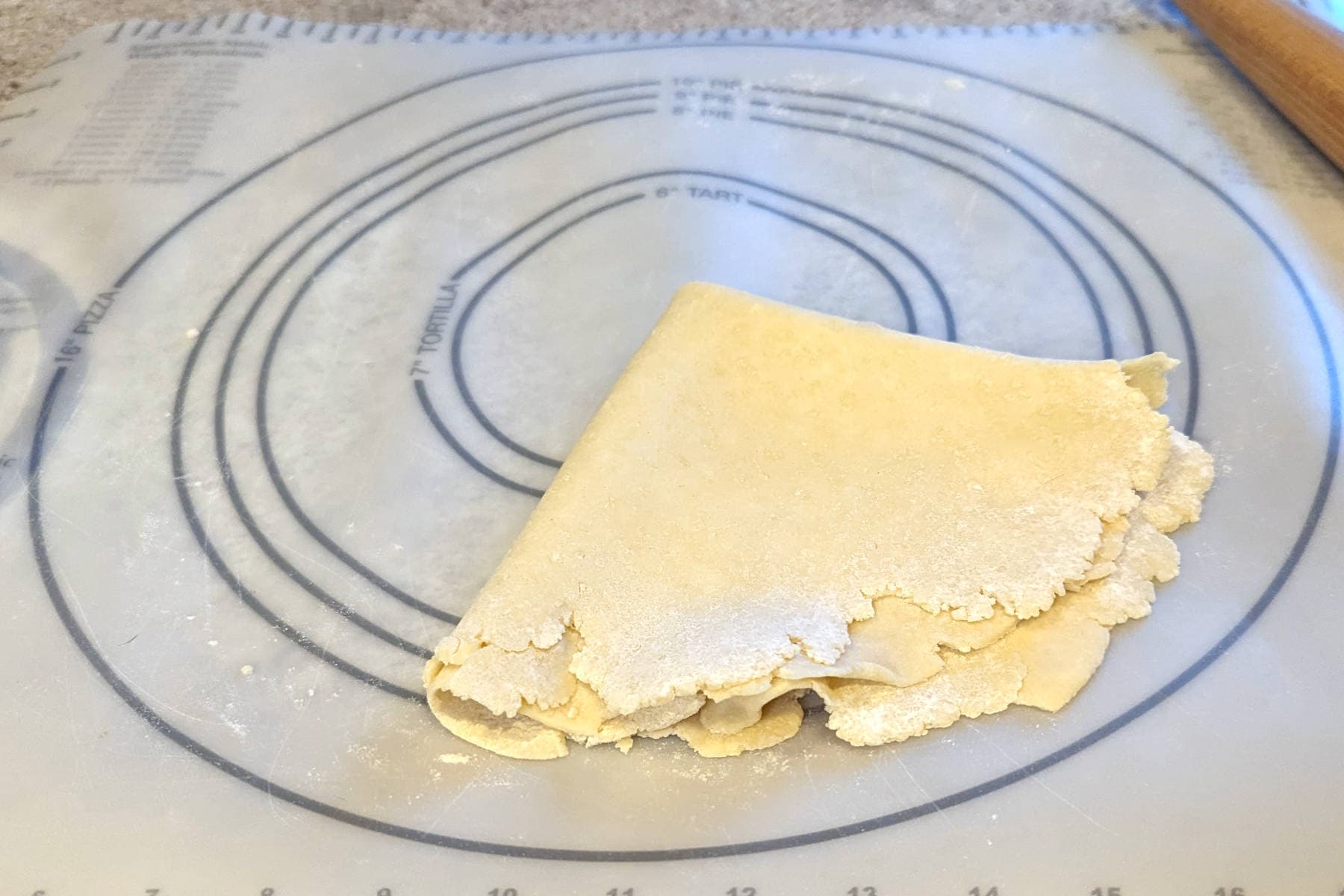 pie crust dough, rolled out and folded into quarters on a rolling mat