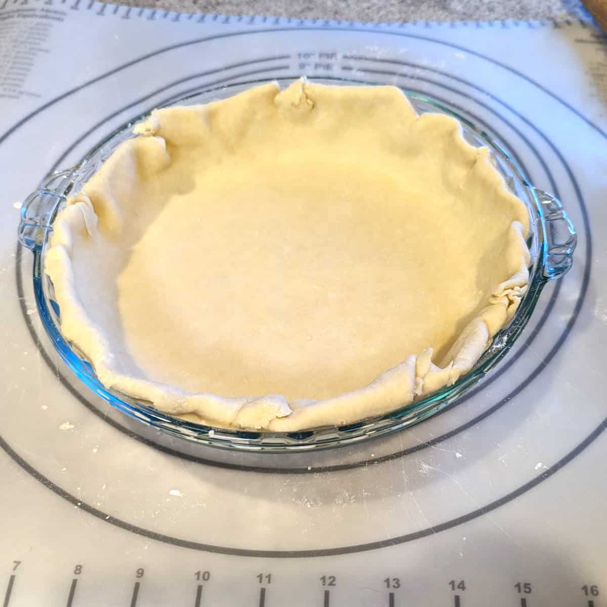 pie crust dough with all rough edges folded underneath themselves, between the pie plate and the pie dough itself