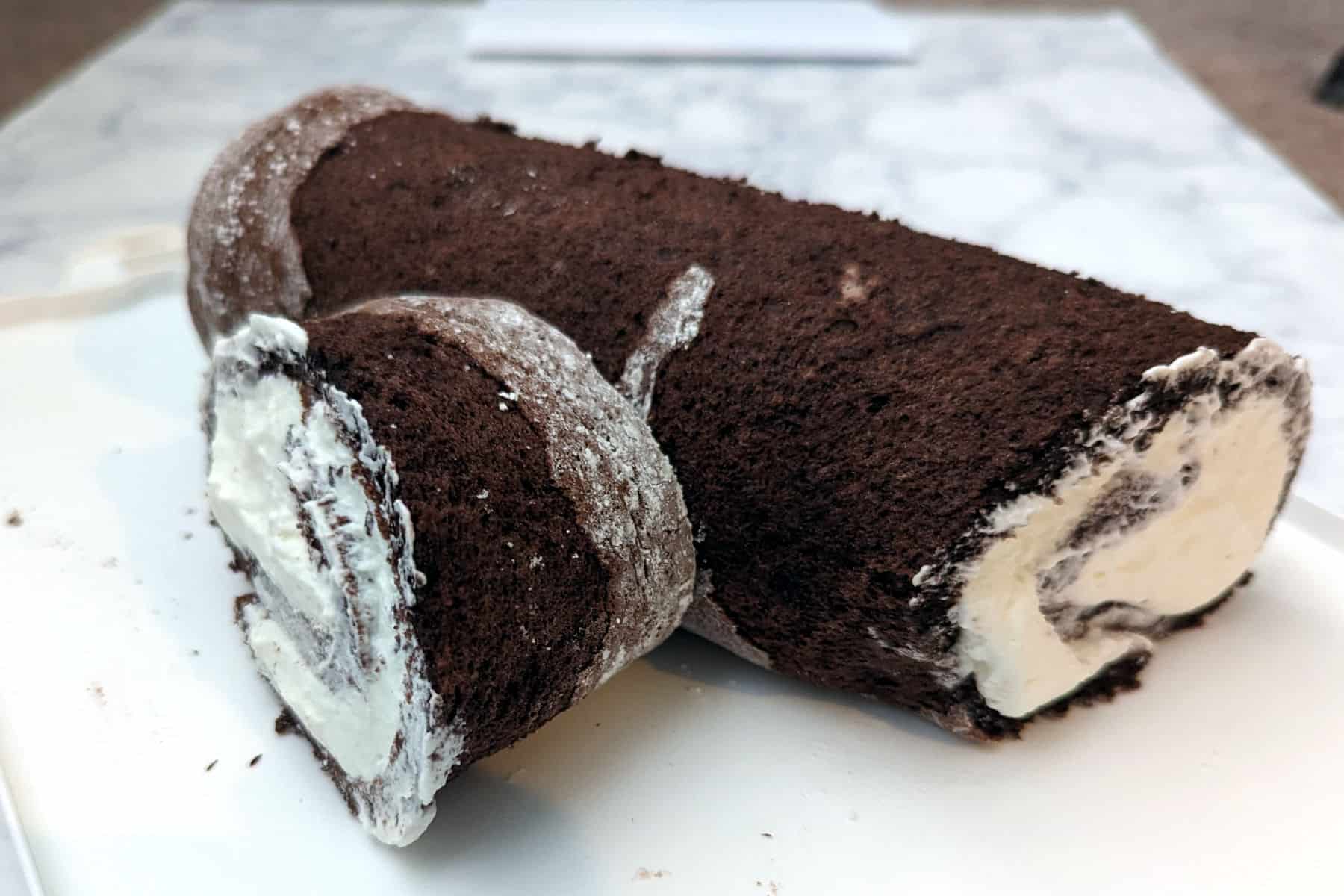 cut part of the swiss cake roll arranged next to the main branch of the yule log