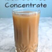 Iced coffee from cold brew coffee concentrate, in a glass with an ice cube. Text for Pinterest reads: "Cold Brew Iced Coffee Concentrate."