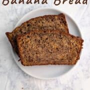 Two slices of banana bread, stacked and staggered, on a plate. Text overlay for Pinterest reads "Classic Banana Bread With Oats!"