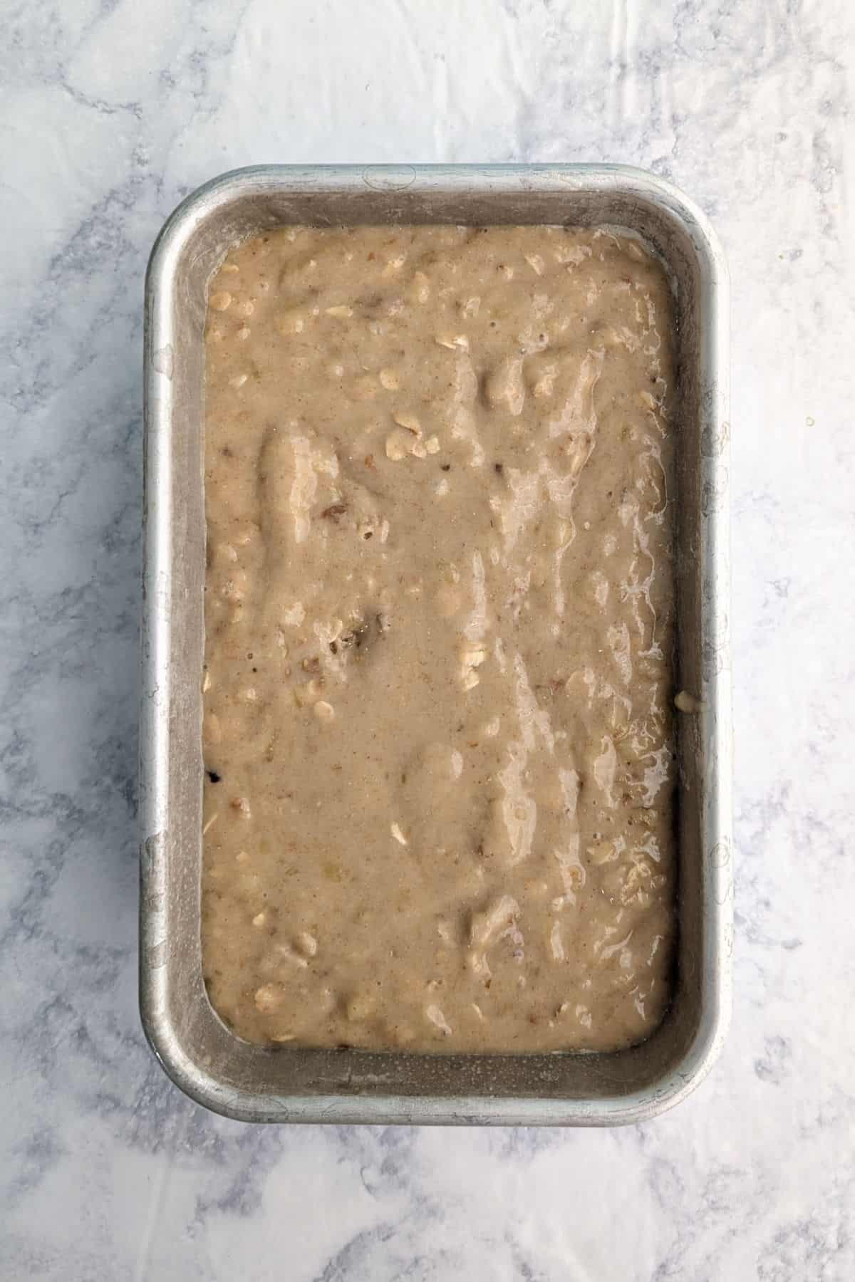 Banana bread batter in a metal loaf pan.