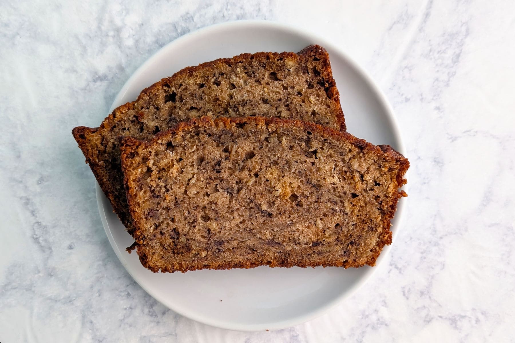 Two slices of banana bread, stacked and staggered, on a plate.