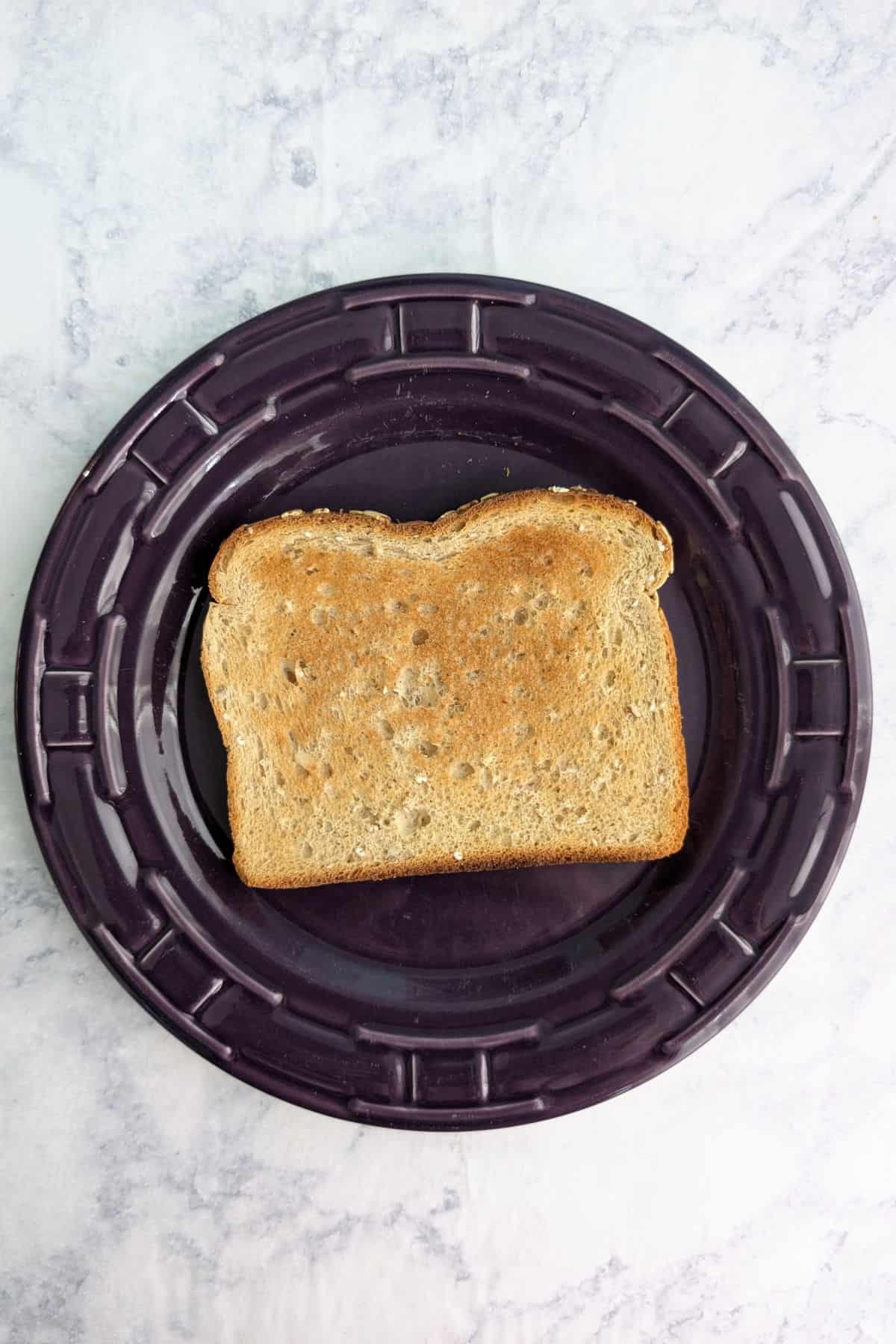 A piece of toast on a purple plate.