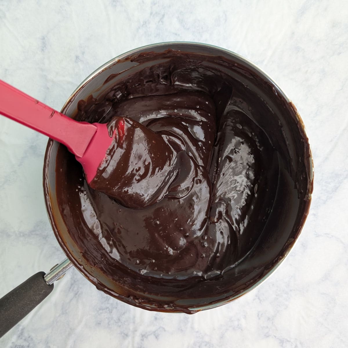 Melted chocolate ganache in a saucepan.