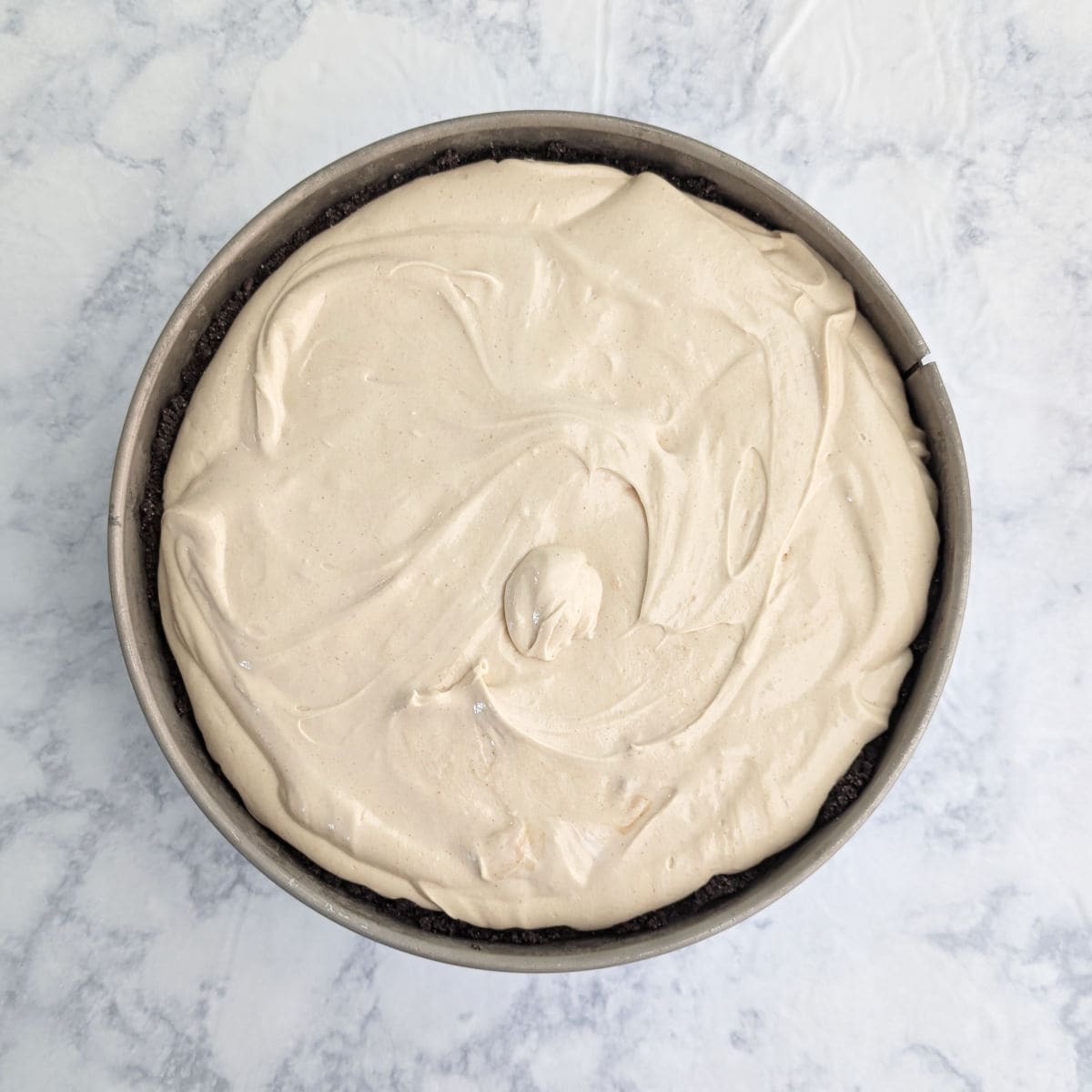 Peanut butter cheesecake batter in a crust in a springform pan.