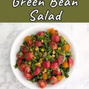 Corn and green bean salad with tomatoes and cilantro on top. Text overlay for Pinterest reads "Corn & Green Bean Salad with Lime."