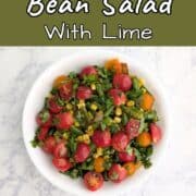 Corn and green bean salad with tomatoes and cilantro on top. Text overlay for Pinterest reads "Corn & Green Bean Salad with Lime."