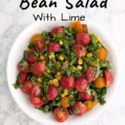 Corn and green bean salad with tomatoes and cilantro on top. Text overlay for Pinterest reads "Corn & Green Bean Salad with Lime."