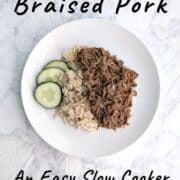 Soy-Cola Braised Pork, plated alongside brown rice and cucumbers. Text overlay for Pinterest reads "An Easy Slow Cooker Recipe!"