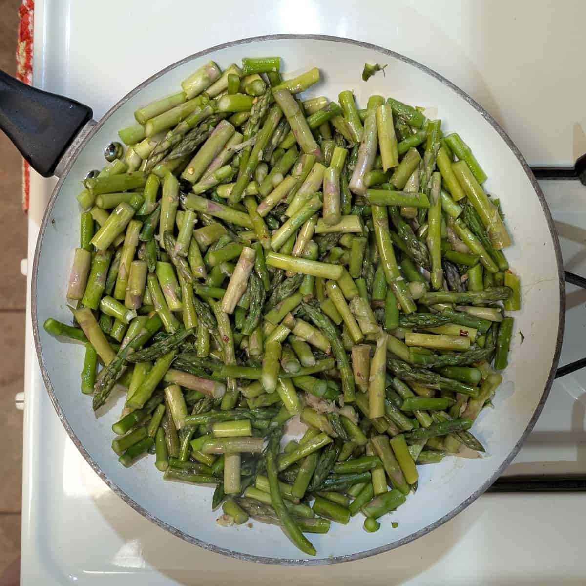 1-inch pieces of asparagus, in a skillet on a stove.