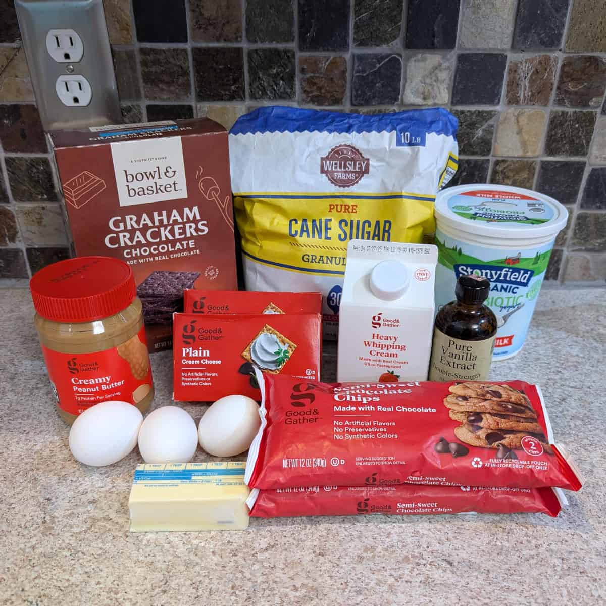 Ingredients for chocolate peanut butter cheesecake: chocolate graham crackers, sugar, yogurt, peanut butter, eggs, cream cheese, heavy cream, vanilla extract, chocolate chips, butter.