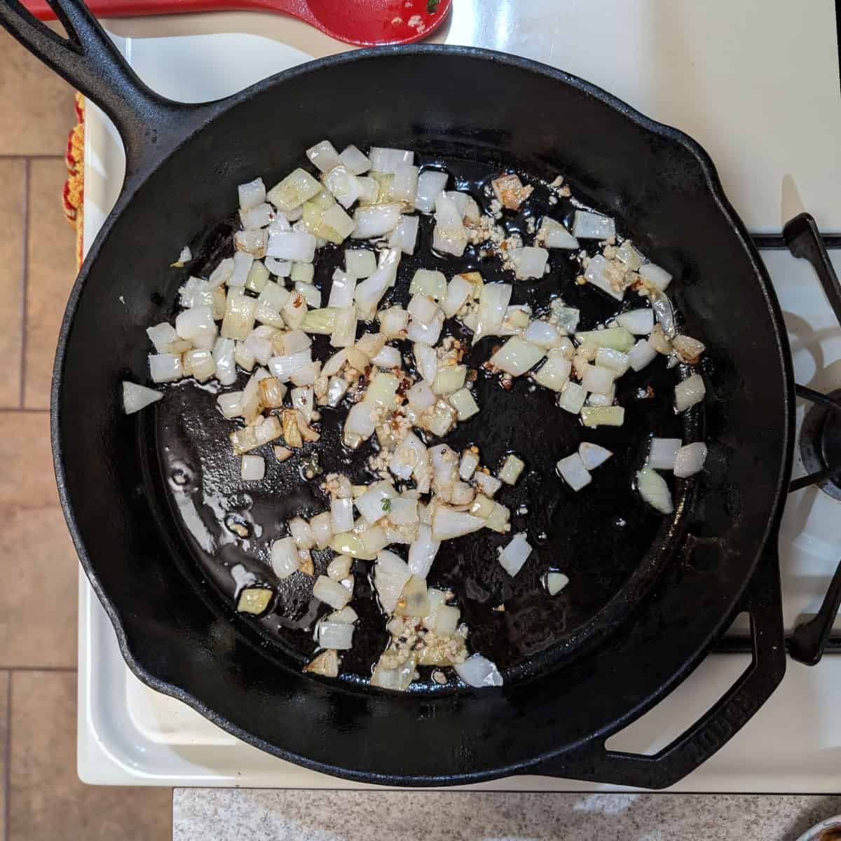 A cast iron skillet with sauteed onion and garlic.