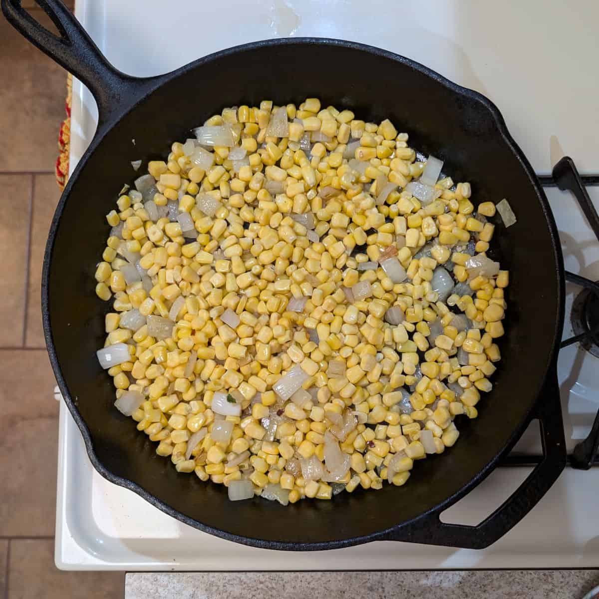 A cast iron skillet with sauteed onion and corn.