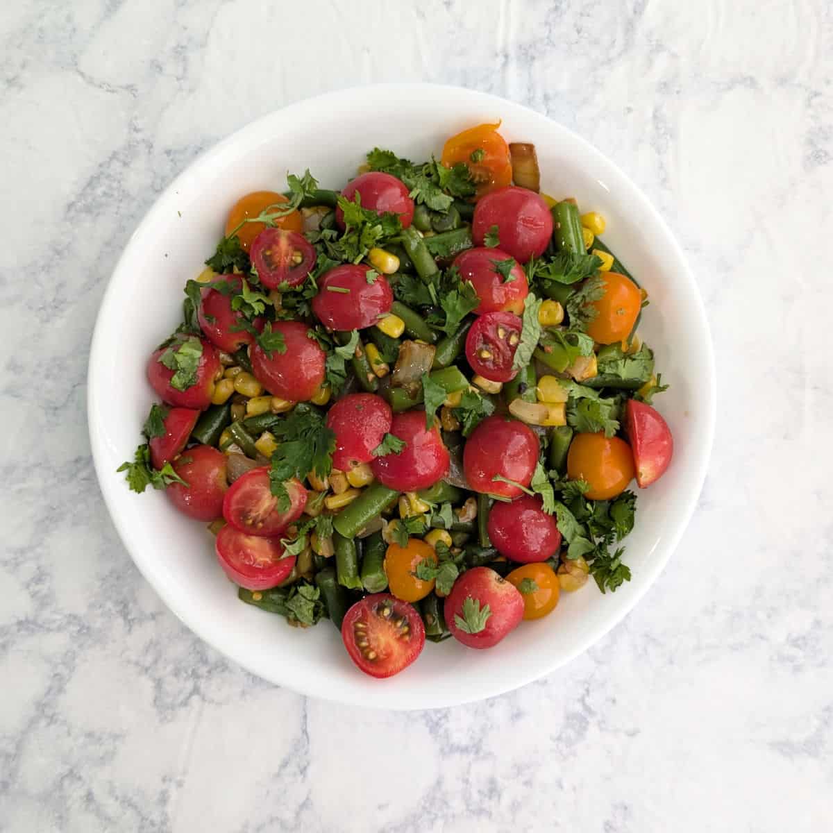Corn and green bean salad with tomatoes and cilantro on top.