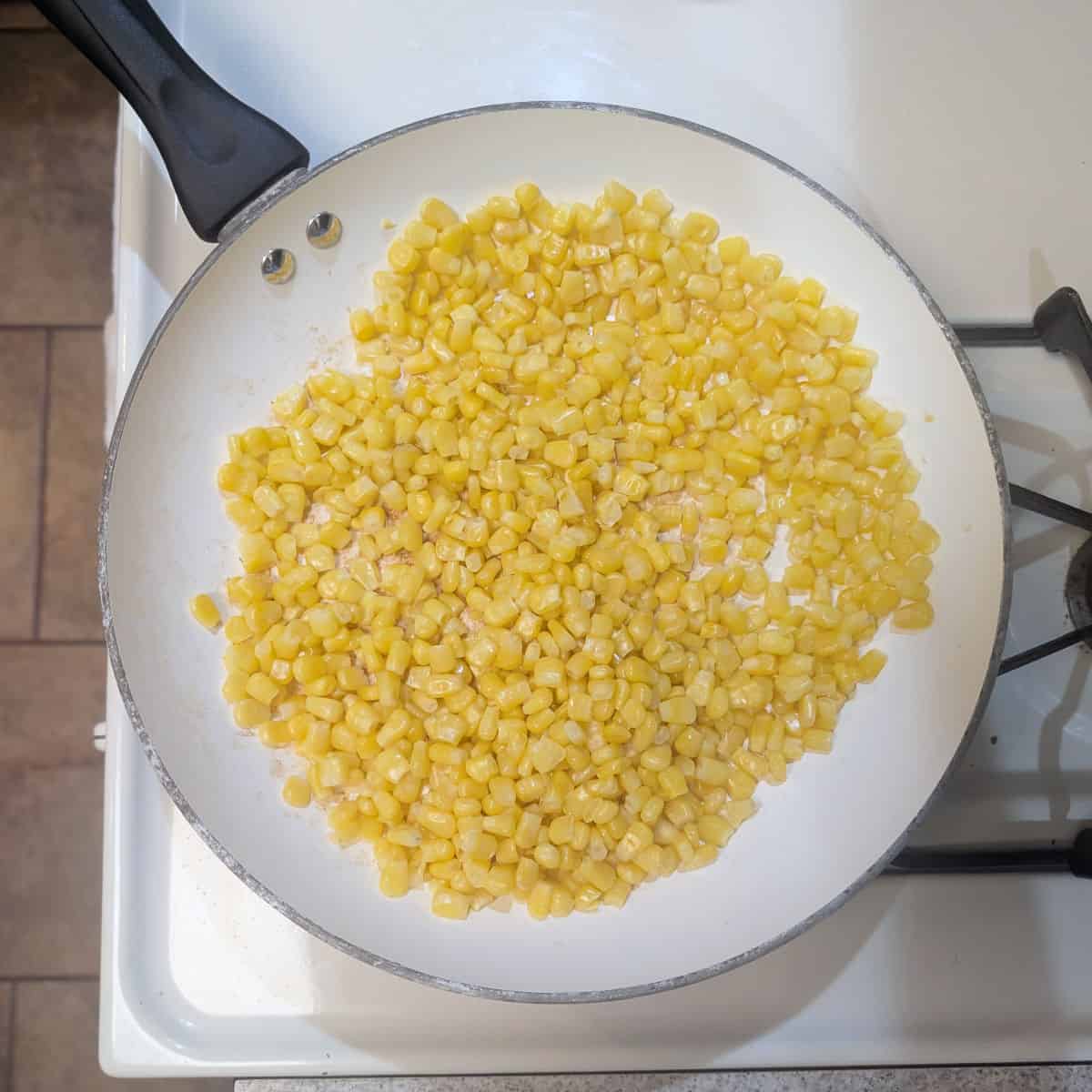 Corn in a skillet on a stove.