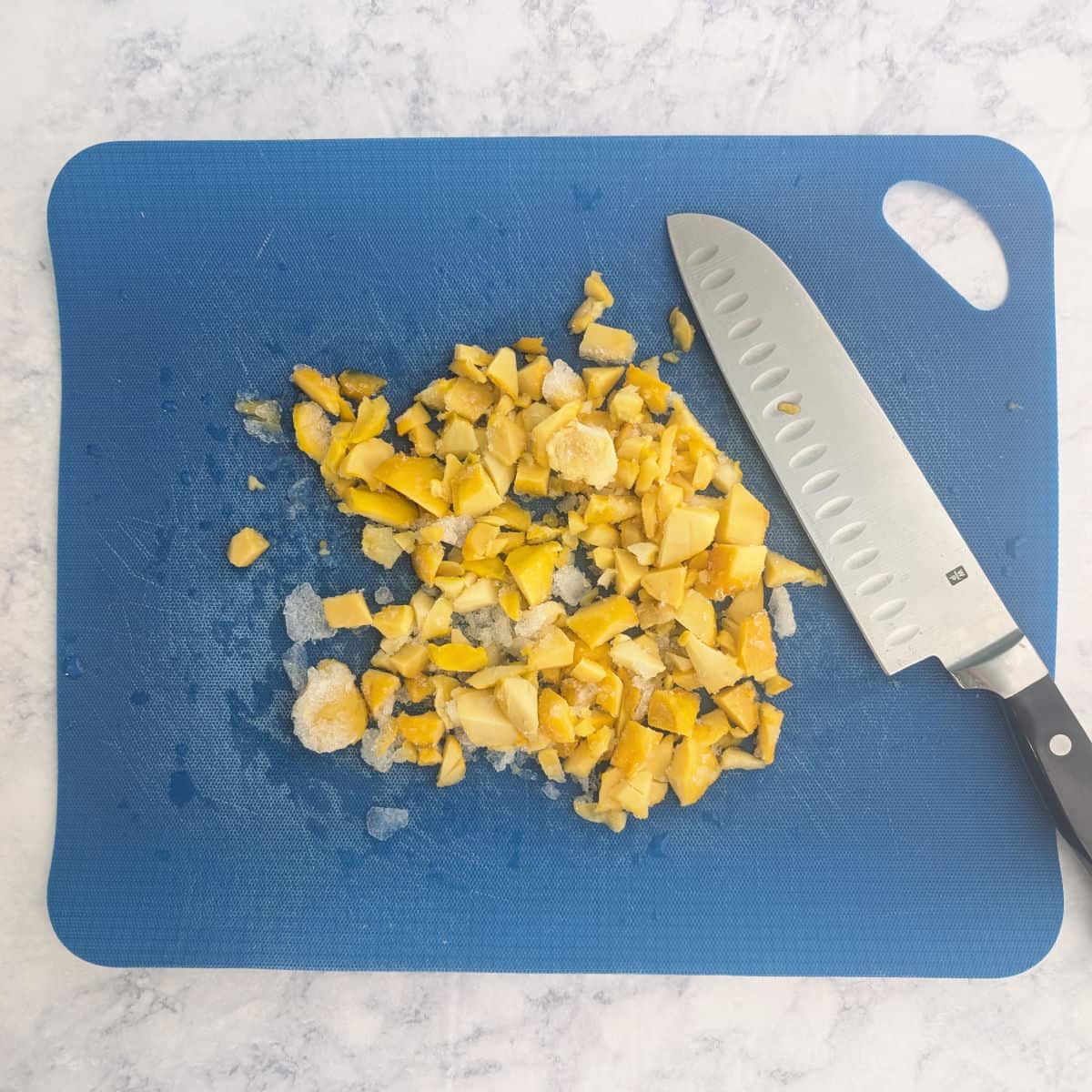 Chopped frozen mango on a cutting board.