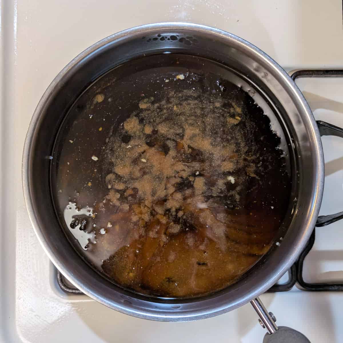 Soy-cola braising liquid in a pot on the stove.