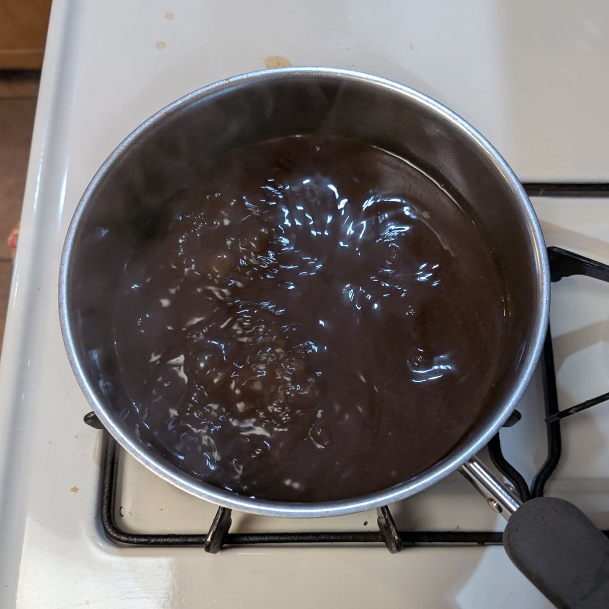 Soy-cola sauce in a pot on the stove, having been reduced by half.