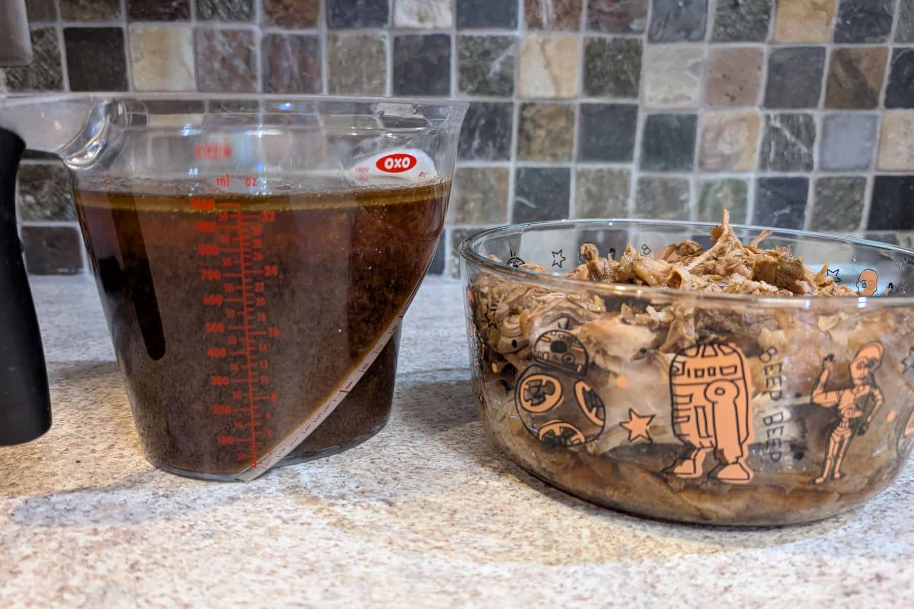A 4-cup measuring cup holding soy-cola braising liquid, next to a 7-cup glass Pyrex container holding shredded pork.