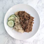 Soy-Cola Braised Pork, plated alongside brown rice and cucumbers.