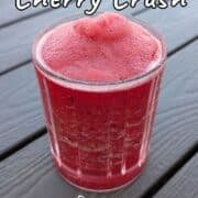 Bourbon cherry crush, a slushy alcoholic drink, in a glass on an outdoor picnic table. Text overlay for Pinterest reads, "Refreshing. Not Too Sweet!"