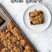 A chocolate oat bar on a plate, next to a pan with the remaining bars. Text overlay for Pinterest reads "Chocolate Oat Bars. Rich and Decadent!"