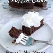 A bite of chocolate truffle cake on a fork, next to a slice of cake with whipped cream. The remaining cake is on a plate in the background.