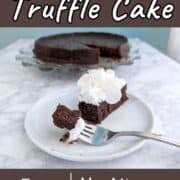 A bite of chocolate truffle cake on a fork, next to a slice of cake with whipped cream. The remaining cake is on a plate in the background.