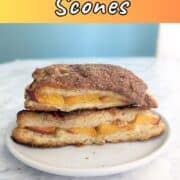 Two stacked peach cobbler scones on a plate. Text overlay for Pinterest reads "Peach Cobbler Scones. Sweet & Delicious!"