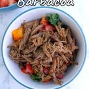 A bowl of shredded barbacoa beef, garnished with peppers and cilantro.