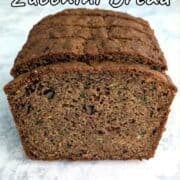 A slice of whole wheat zucchini bread in front of a stack of zucchini bread.