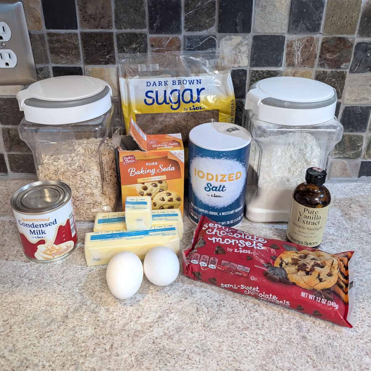 Ingredients for chocolate oat bars: rolled oats, brown sugar, flour, sweetened condensed milk, baking soda, salt, butter, eggs, chocolate chips, and vanilla extract.