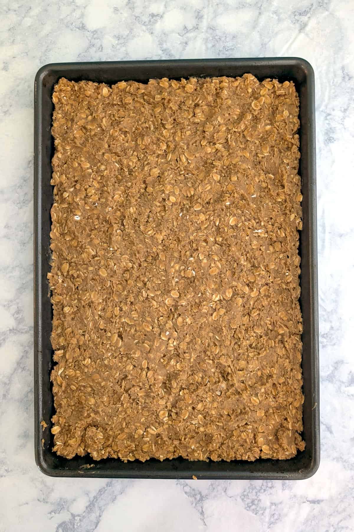 Oatmeal cookie dough, patted into a jelly roll pan.