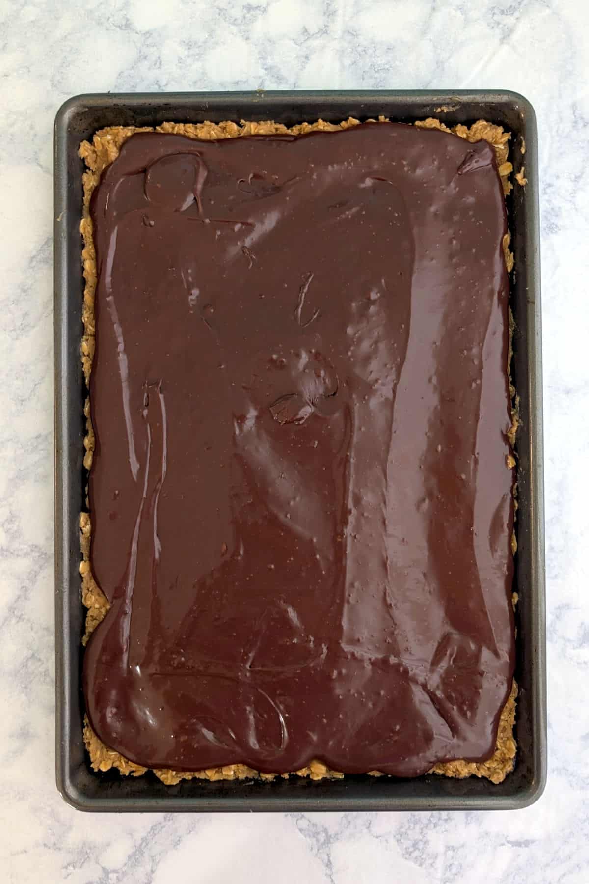 Chocolate fudge layered over oatmeal cookie dough, in a jelly roll pan.