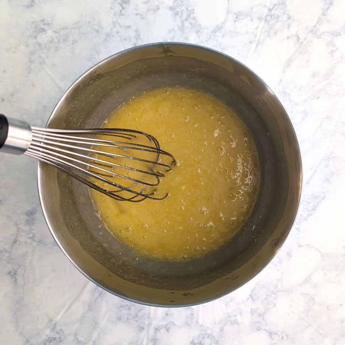 Eggs and sugar, mixed together in a mixing bowl.