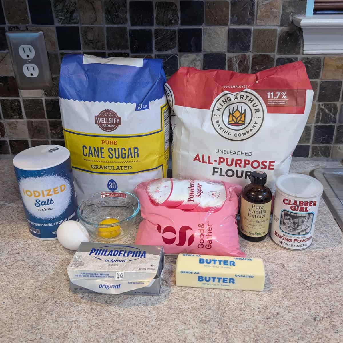 Sugar, flour, salt, baking powder, vanilla extract, an egg, an egg yolk, cream cheese, butter, and powdered sugar.