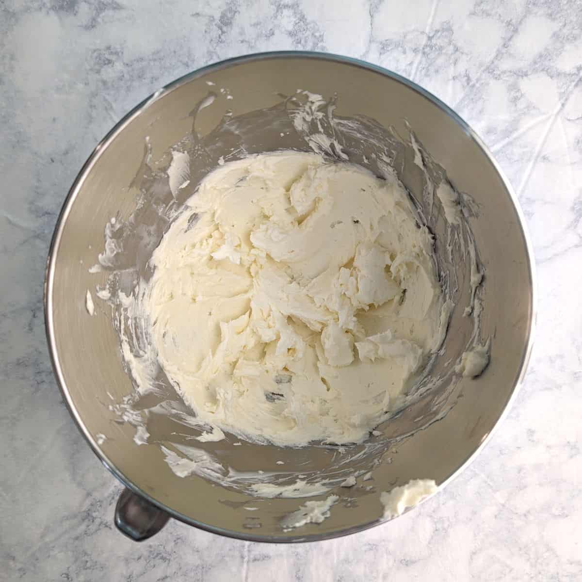 Butter and cream cheese, mixed together in a stand mixer bowl.