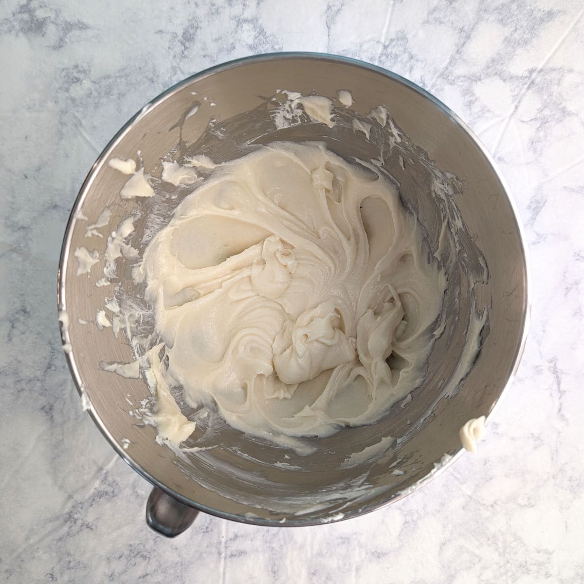 Butter, cream cheese, and sugar, mixed together in a stand mixer bowl.