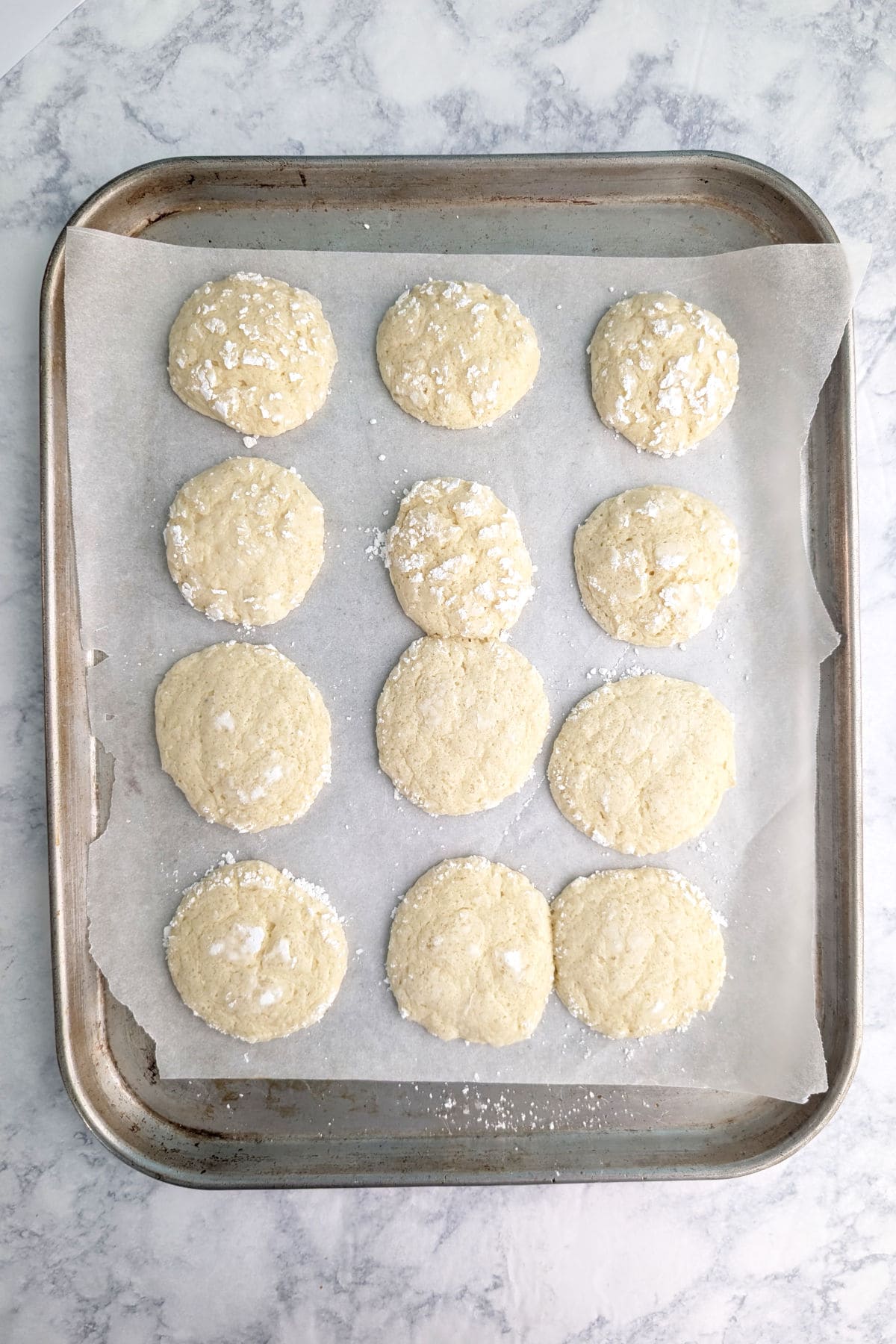 Gooey butter cookies, baked, on parchment paper on a baking sheet.