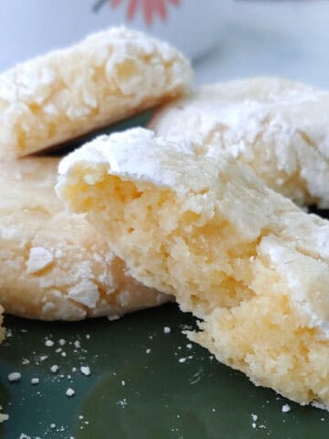 Gooey butter cookies on a plate, with one torn open to show texture.