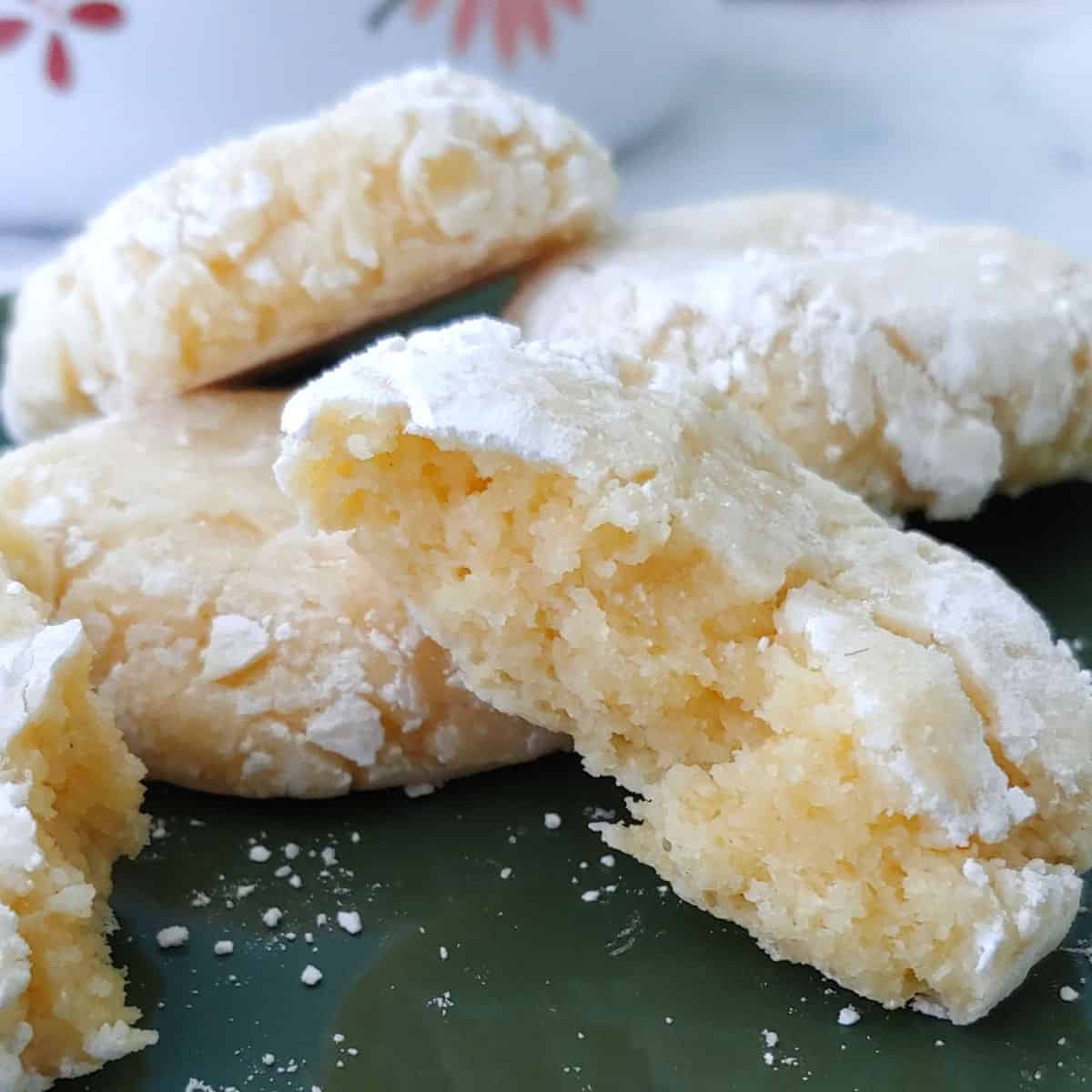 Gooey butter cookies on a plate, with one torn open to show texture.