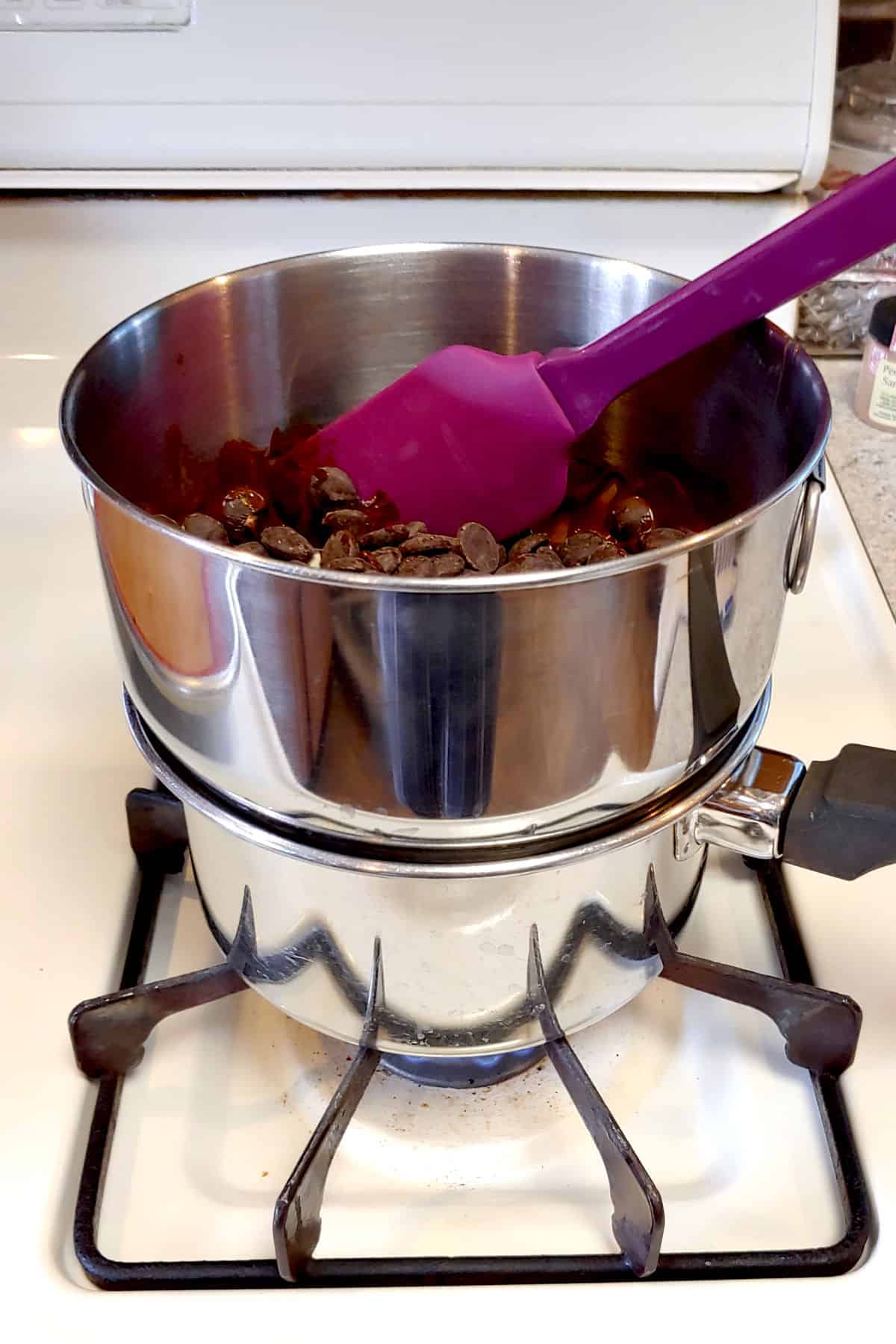 Chocolate and butter in a medium sized mixing bowl that rests snugly on a medium-sized saucepan with water, creating a makeshift double boiler.