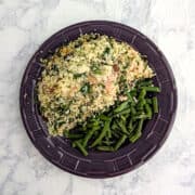 Salmon with Baked Couscous, alongside green beans on a purple plate.