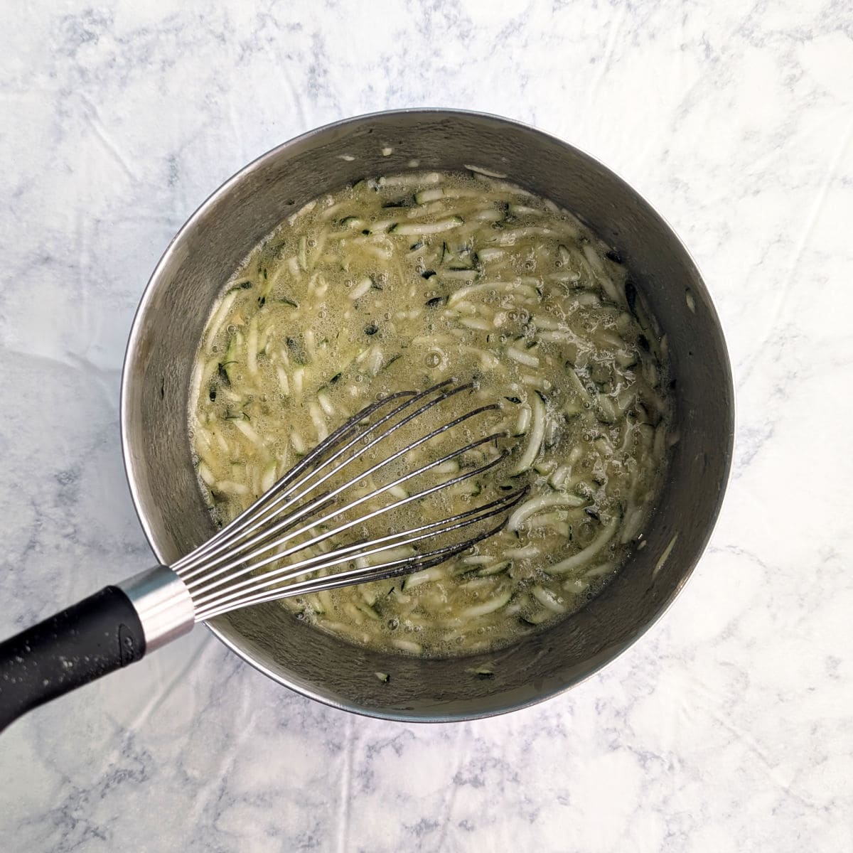 Eggs, sugar, vegetable oil, and shredded zucchini, in a mixing bowl.