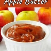 No-sugar-added slow cooker apple butter in a ramekin, in front of apples. Text overlay for Pinterest reads "Slow Cooker Apple Butter. No Sugar Added!"