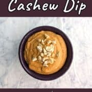 Smoky cashew dip, garnished with chopped cashews, in a small purple ramekin. Text overlay for Pinterest reads "Smoky Cashew Dip. 2 Ingredients. 5 Minutes."