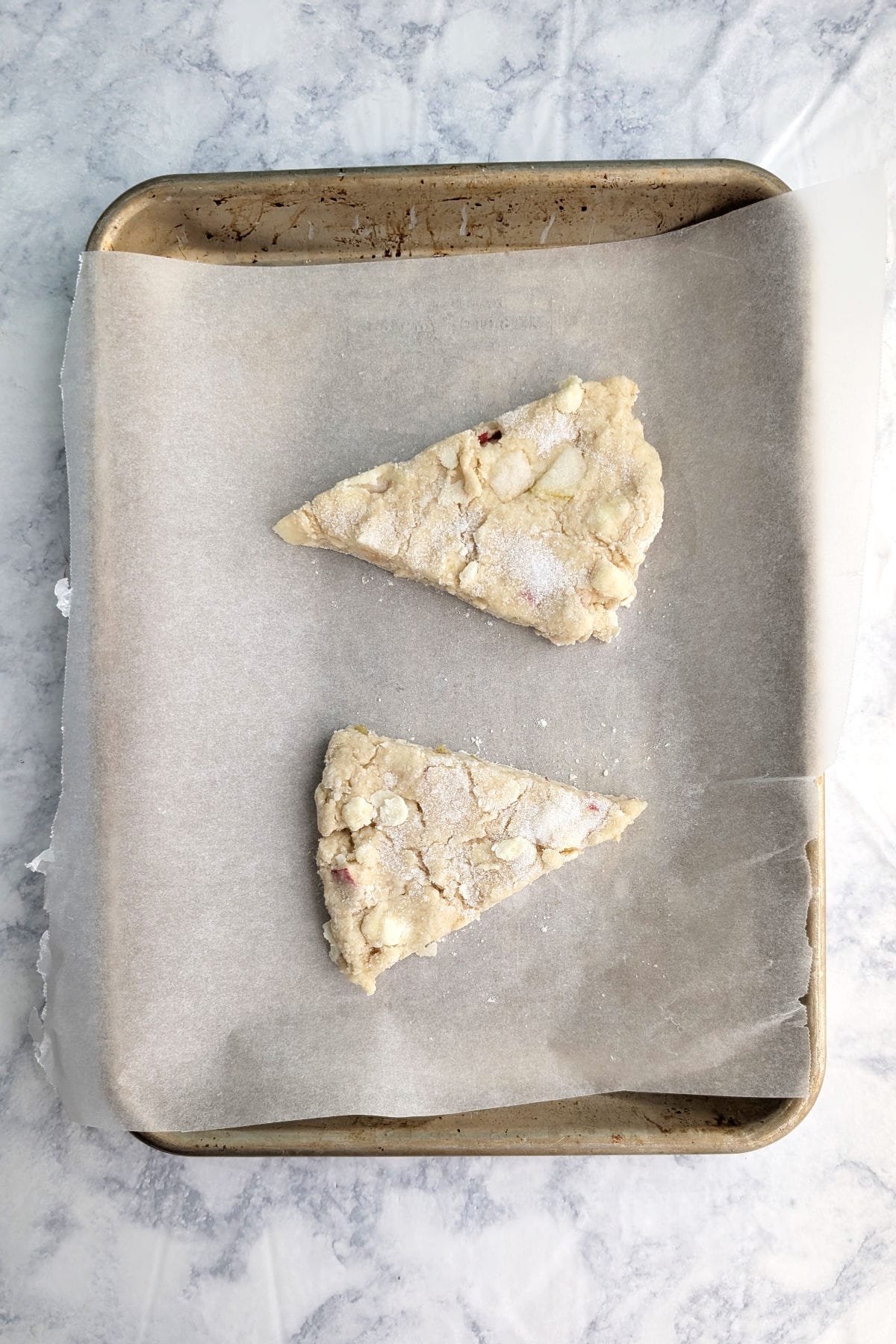 Wedges of scone dough, on a baking sheet covered with parchment paper.